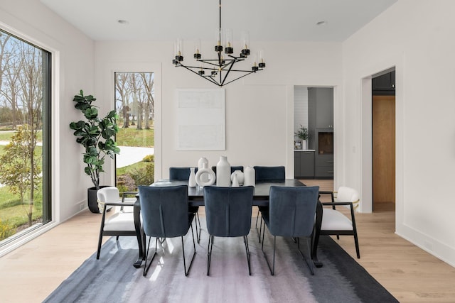 dining space with a healthy amount of sunlight, a chandelier, and light wood-type flooring