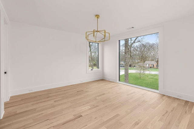 unfurnished dining area with a chandelier and light wood-type flooring