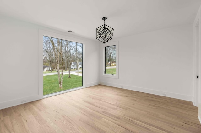 unfurnished dining area with a notable chandelier and light hardwood / wood-style flooring