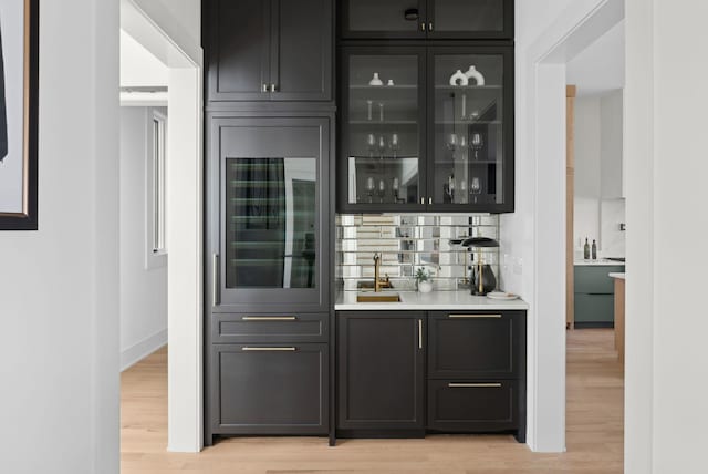 bar with tasteful backsplash, sink, wine cooler, and light hardwood / wood-style flooring