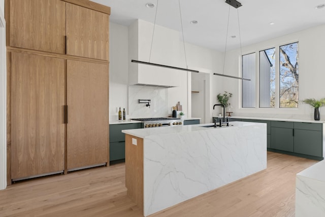 kitchen with pendant lighting, tasteful backsplash, an island with sink, sink, and green cabinets