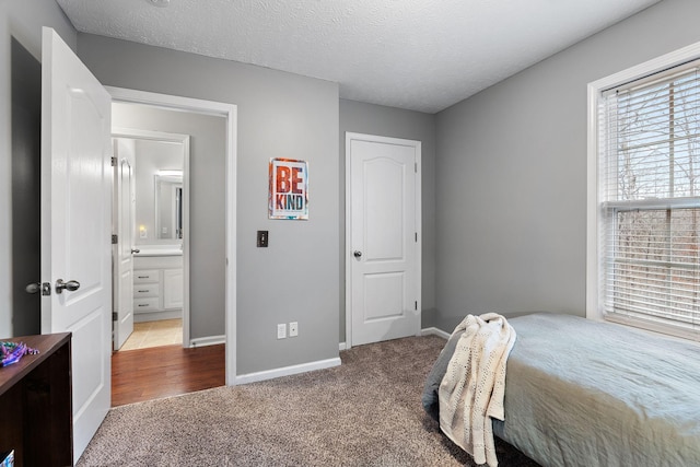 bedroom with connected bathroom, carpet floors, and a textured ceiling