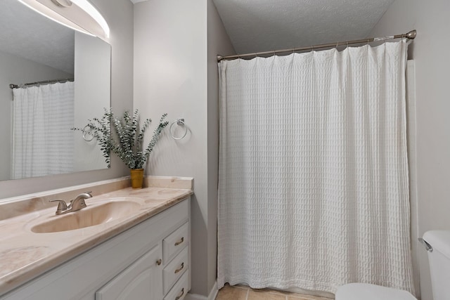 bathroom featuring tile patterned flooring, a textured ceiling, vanity, and toilet