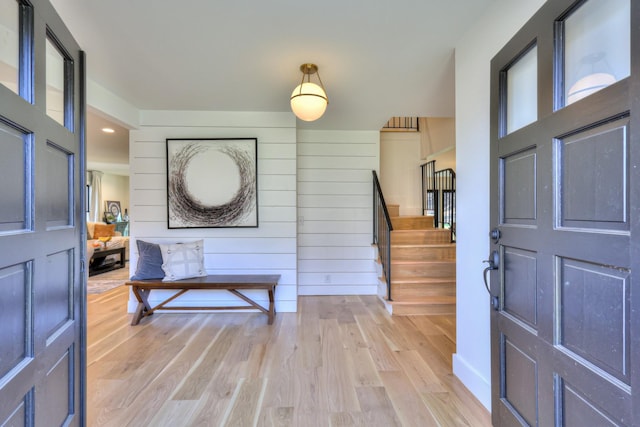 foyer with light hardwood / wood-style floors and wooden walls