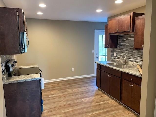 kitchen with backsplash, dark brown cabinets, light wood-type flooring, and sink