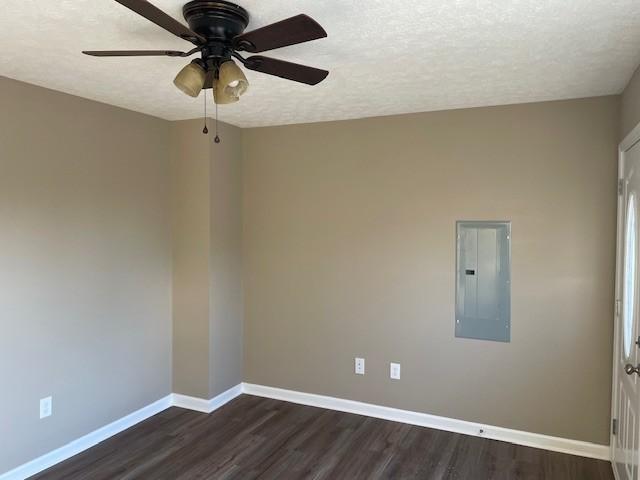 unfurnished room with electric panel, ceiling fan, dark hardwood / wood-style floors, and a textured ceiling