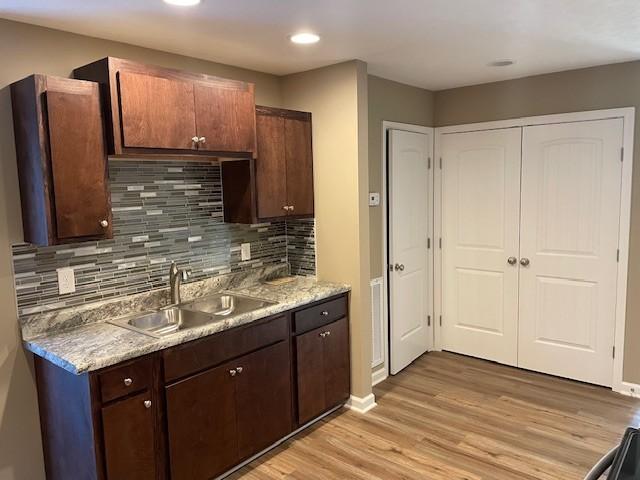 kitchen featuring tasteful backsplash, sink, dark brown cabinets, and light hardwood / wood-style flooring