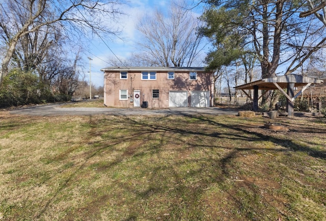 rear view of house featuring a garage and a lawn