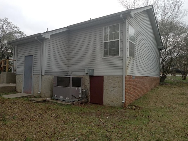 back of property featuring a lawn and central AC