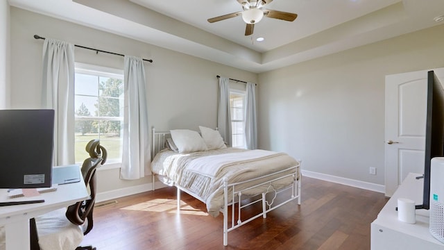 bedroom featuring wood-type flooring, a tray ceiling, and ceiling fan