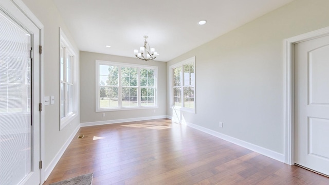 unfurnished dining area with wood-type flooring and an inviting chandelier