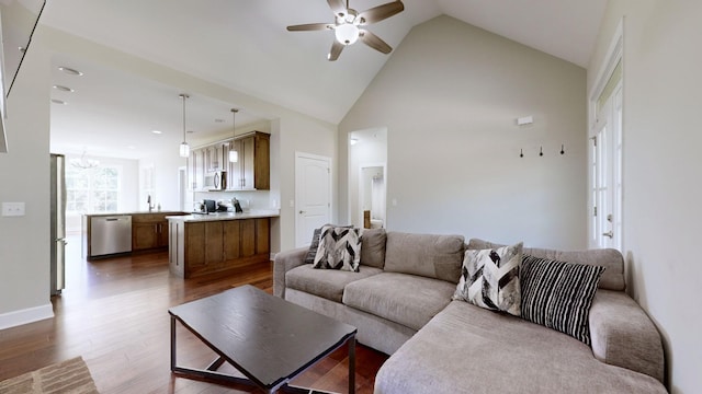 living room with ceiling fan with notable chandelier, dark hardwood / wood-style flooring, sink, and high vaulted ceiling