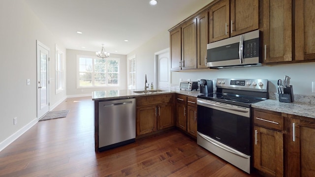 kitchen featuring light stone countertops, stainless steel appliances, dark hardwood / wood-style flooring, kitchen peninsula, and a chandelier