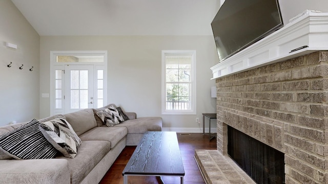 living room featuring dark hardwood / wood-style flooring, vaulted ceiling, and a brick fireplace