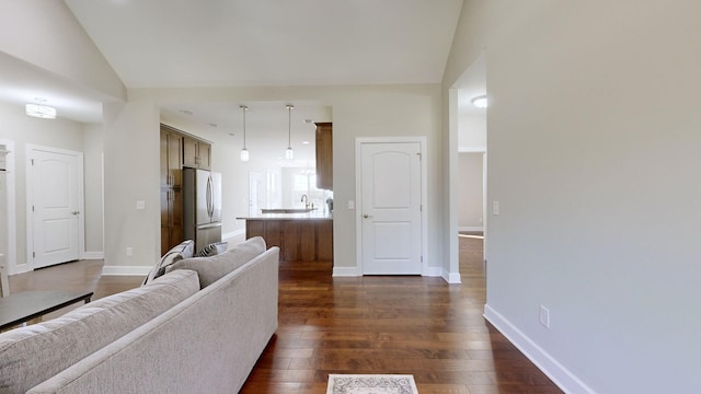 living room with sink, lofted ceiling, and dark wood-type flooring