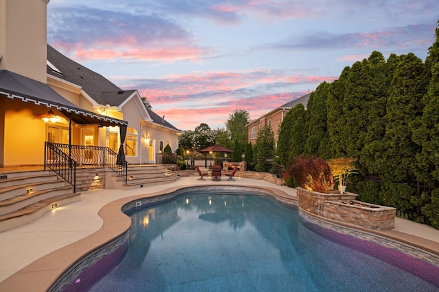 pool at dusk featuring a patio