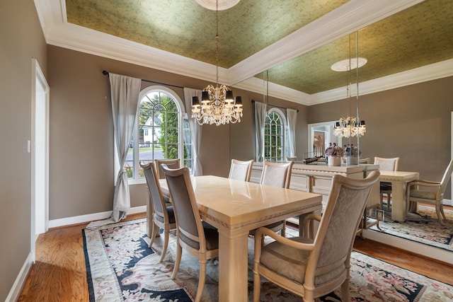 dining area with hardwood / wood-style floors, ornamental molding, a tray ceiling, and a chandelier