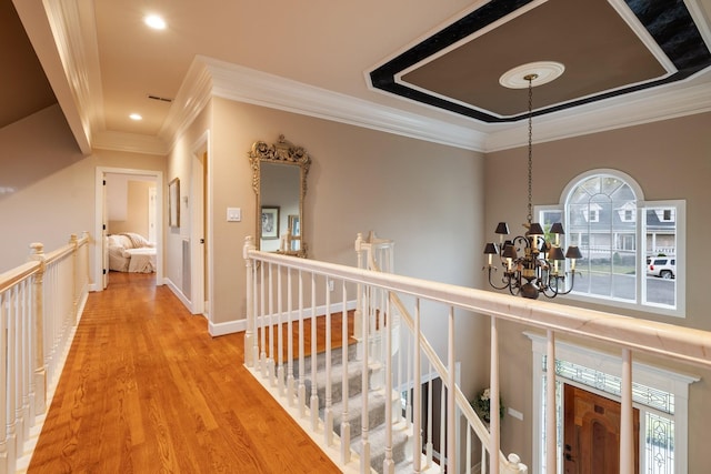 hallway featuring a notable chandelier, light wood-type flooring, and crown molding