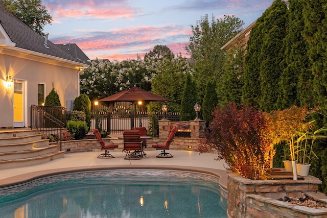 pool at dusk with a gazebo and a patio area