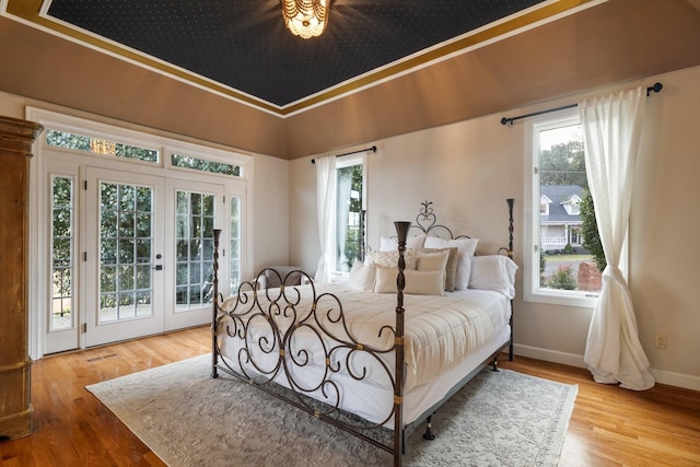 bedroom with ornamental molding, access to outside, multiple windows, and light hardwood / wood-style floors