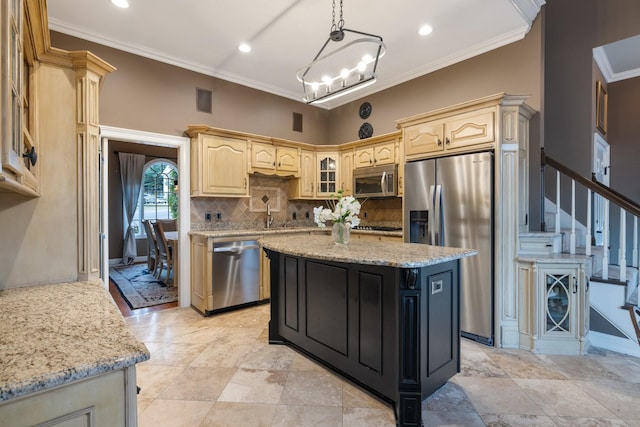 kitchen featuring light stone countertops, ornamental molding, appliances with stainless steel finishes, decorative light fixtures, and a kitchen island