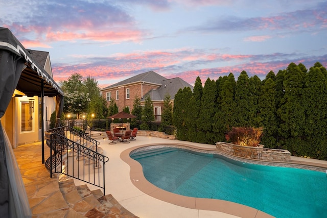 pool at dusk with a patio area