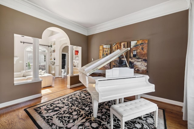 miscellaneous room with hardwood / wood-style flooring, crown molding, and decorative columns