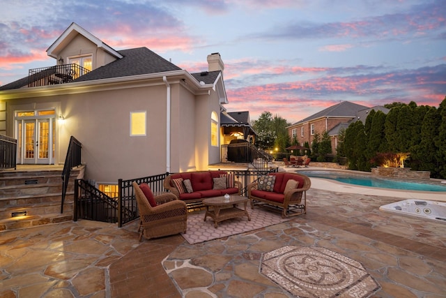 patio terrace at dusk featuring a balcony, an outdoor hangout area, and french doors