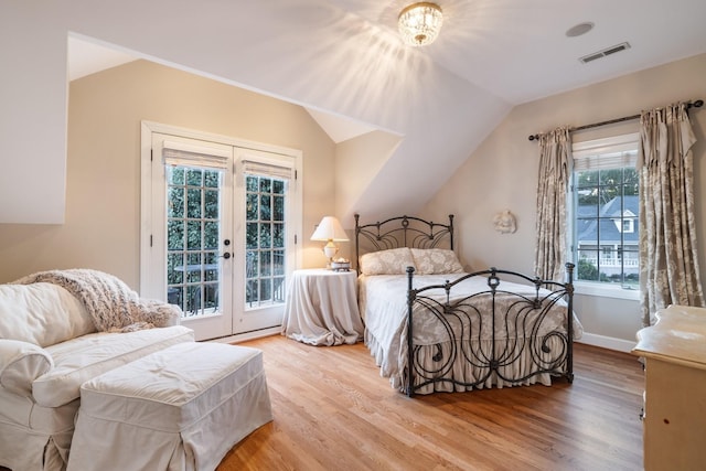 bedroom featuring access to exterior, french doors, light wood-type flooring, and lofted ceiling