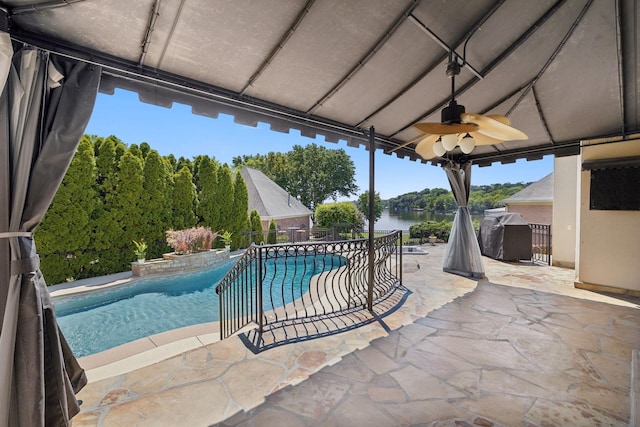 view of pool featuring ceiling fan, a water view, a patio, and grilling area