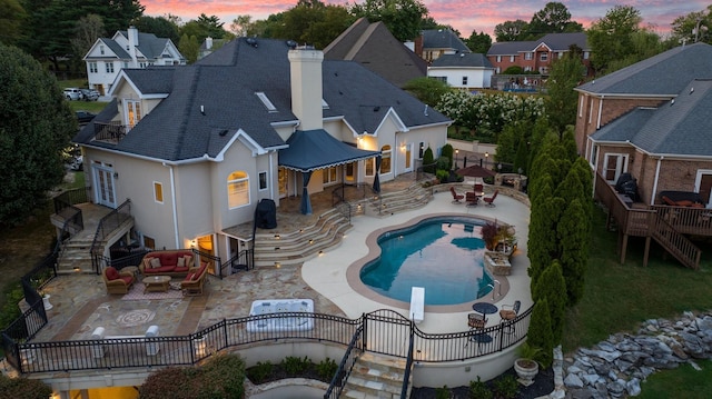 pool at dusk with a patio and an outdoor living space with a fire pit