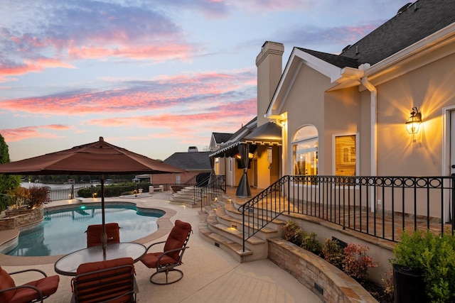 pool at dusk with a gazebo and a patio area