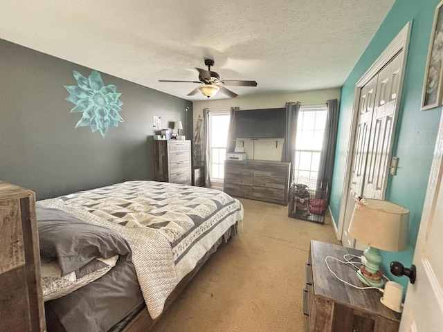 carpeted bedroom with ceiling fan and a textured ceiling