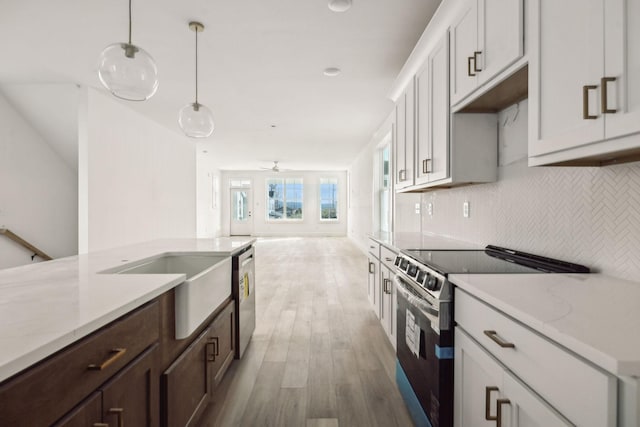 kitchen with pendant lighting, light hardwood / wood-style floors, light stone counters, white cabinetry, and stainless steel appliances