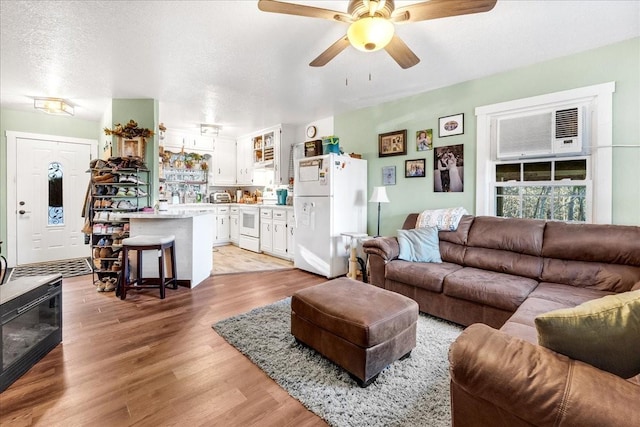 living room with ceiling fan, light hardwood / wood-style floors, and a textured ceiling