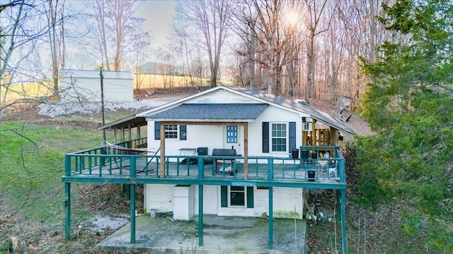 rear view of house with a wooden deck and a patio