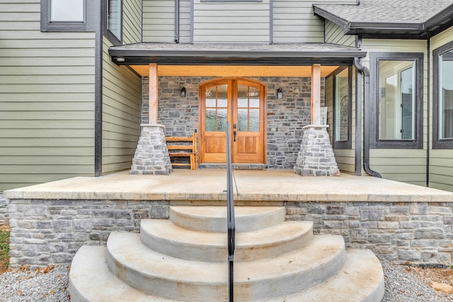 view of exterior entry featuring covered porch and french doors