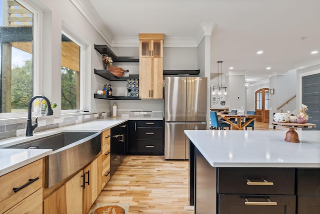 kitchen featuring pendant lighting, light brown cabinets, crown molding, sink, and stainless steel fridge