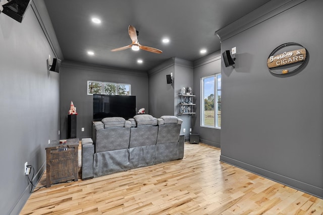 cinema with ceiling fan, light hardwood / wood-style floors, and ornamental molding