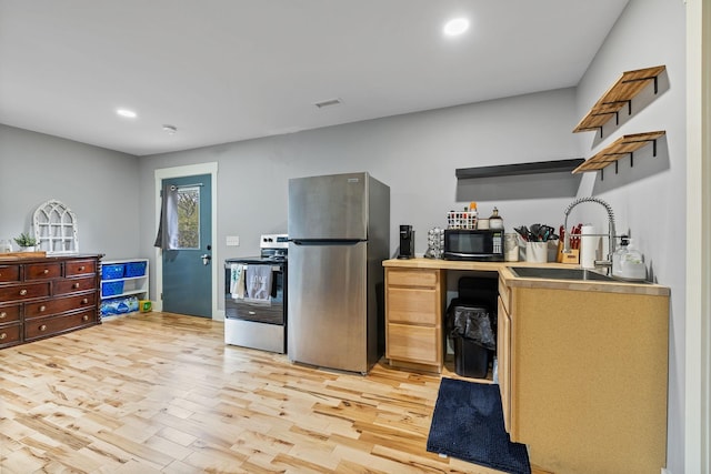 kitchen with light brown cabinetry, light wood-type flooring, stainless steel appliances, and sink