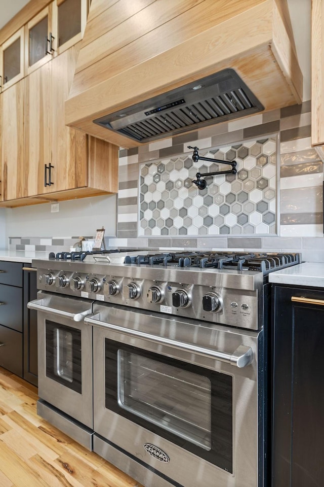 kitchen featuring backsplash, range with two ovens, and light wood-type flooring