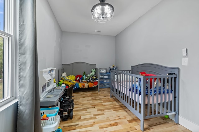 bedroom featuring light hardwood / wood-style floors and a crib