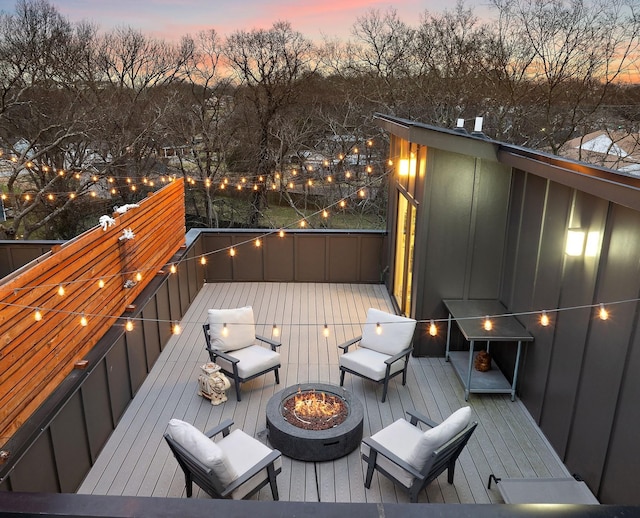 deck at dusk featuring a fire pit