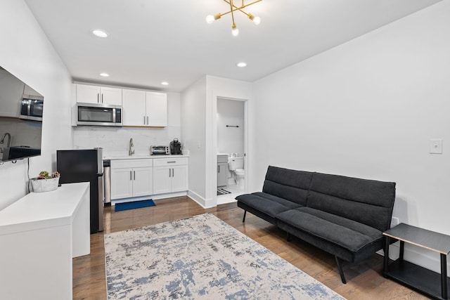 interior space with decorative backsplash, white cabinetry, a notable chandelier, and dark hardwood / wood-style floors