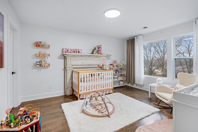 bedroom with dark wood-type flooring and a crib