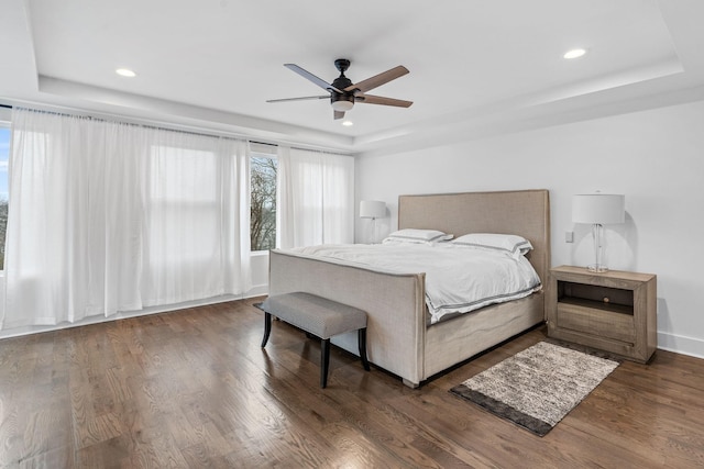 bedroom featuring ceiling fan, dark hardwood / wood-style floors, and a tray ceiling