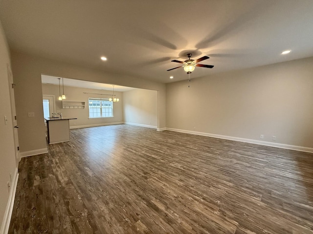 unfurnished living room with ceiling fan with notable chandelier, dark hardwood / wood-style floors, and sink