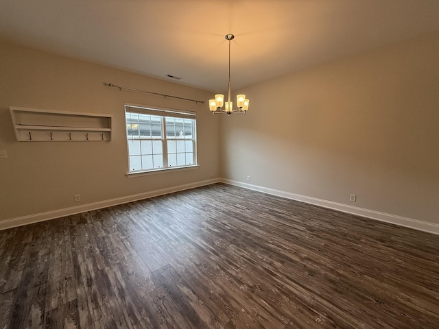 unfurnished room featuring dark hardwood / wood-style flooring and an inviting chandelier