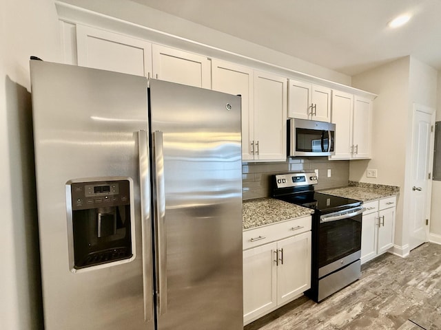 kitchen featuring decorative backsplash, white cabinets, stainless steel appliances, and light wood-type flooring