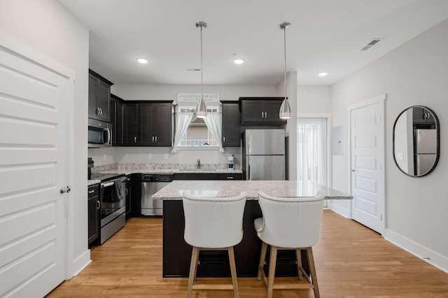 kitchen featuring a center island, pendant lighting, light wood-type flooring, and appliances with stainless steel finishes